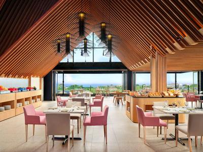 Nowoczesna restauracja z drewnianym sufitem, stołami z krzesłami i dużymi oknami z widokiem.