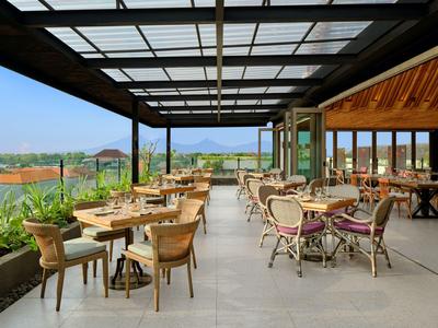 Área exterior cubierta moderna de restaurante con muebles de madera y vistas al paisaje.
