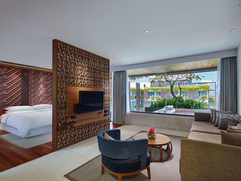 Nowoczesny pokój hotelowy z otwartą częścią dzienną i widokiem na ogród z miejscem do siedzenia.