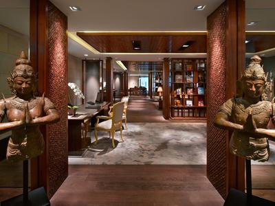 Elegante area dell'hotel con sculture, gruppi di sedute e scaffali in luce calda.