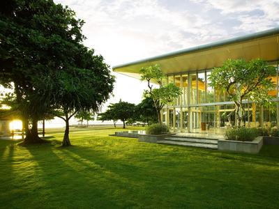 Edificio moderno in vetro accanto a un grande prato con alberi al tramonto