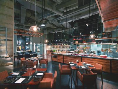 Ristorante moderno con illuminazione elegante, mobili in legno e soffitto aperto.