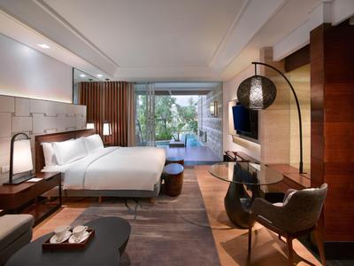 Camera d'albergo moderna con letto grande, zona salotto e vista sul giardino