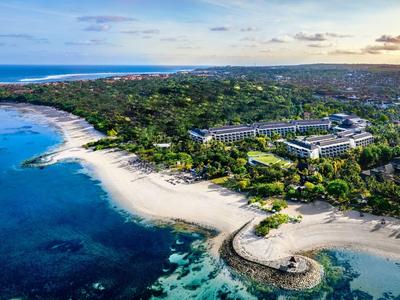 Vista aerea di un hotel sulla spiaggia con acqua blu chiara e vegetazione verde