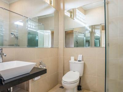Modern bathroom with sink, toilet, and glass shower in a bright setting.