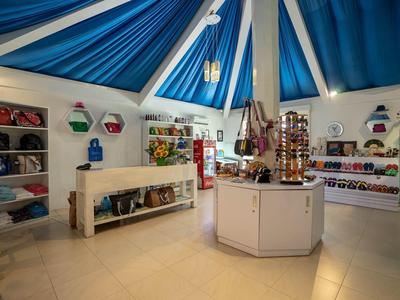 Interior of a souvenir shop with merchandise shelves under a blue tent roof.