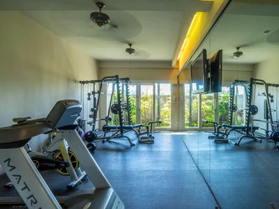 Vue sur un jardin tropical avec des palmiers devant des montagnes et un ciel bleu.