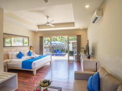 Bright hotel room with double bed, balcony, sofa, and modern amenities.