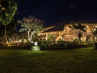 Illuminated hotel building with garden at night under a clear sky.