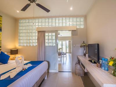 Bright hotel room with double bed, blue and white bedding, and adjoining balcony.