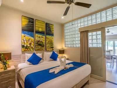 Bright hotel room with double bed, blue pillows, and modern decoration.
