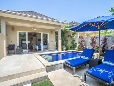 Modern bungalow with private pool, terrace, and blue loungers under a blue umbrella.