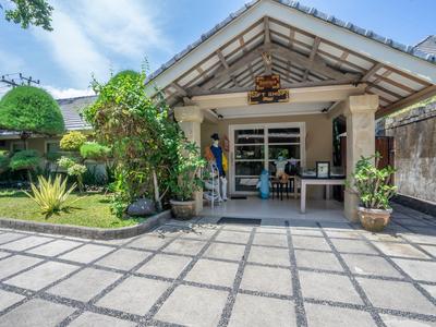 Entrance of a building with open pavilion and paved courtyard under blue sky.