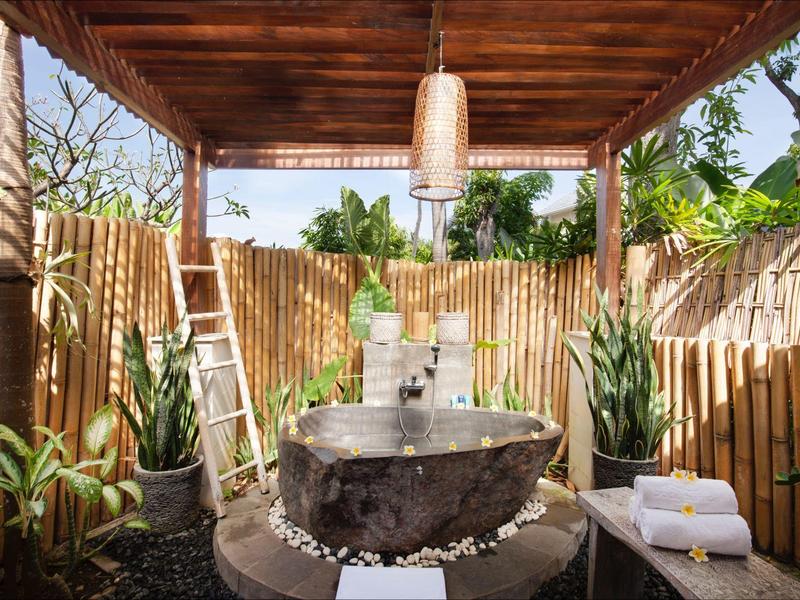 Cozy outdoor area with freestanding bathtub, wooden privacy fence, and plants