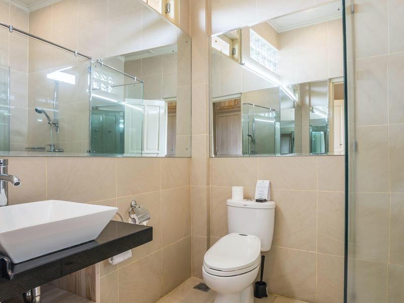 Modern bathroom with sink, toilet, and glass shower in a bright setting.