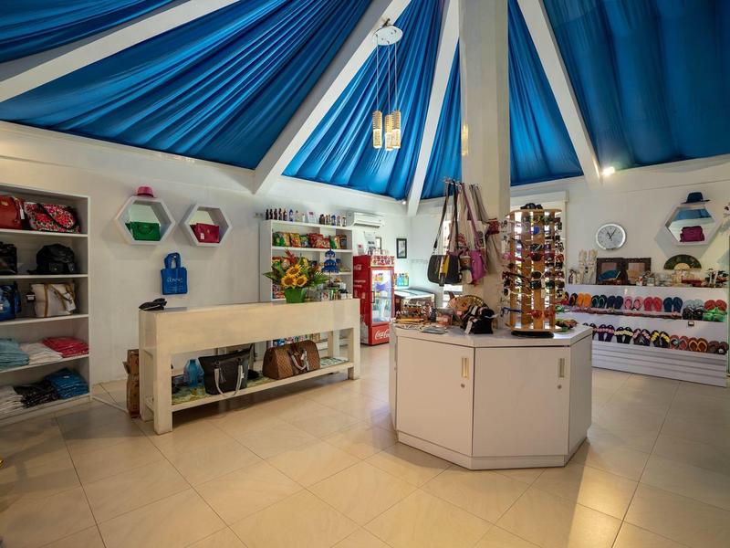 Interior of a souvenir shop with merchandise shelves under a blue tent roof.