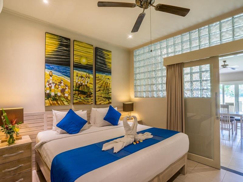 Bright hotel room with double bed, blue pillows, and modern decoration.