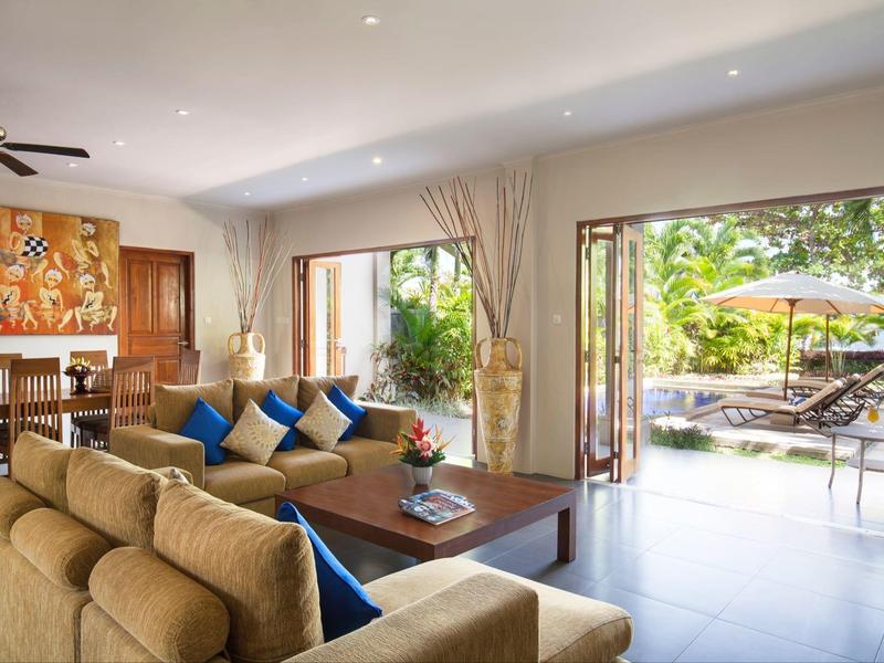 Bright living area with comfortable sofas, view of terrace and garden with sun loungers.