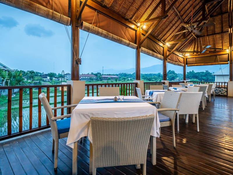 Covered balcony with set tables and chairs overlooking the coastline.