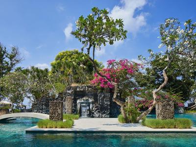 Piscine avec plantes tropicales, arbres et fleurs en fleurs sous un ciel bleu.