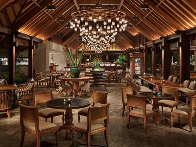 Bar d'hôtel élégante avec boiseries, fauteuils confortables et un lustre en sphères de verre.