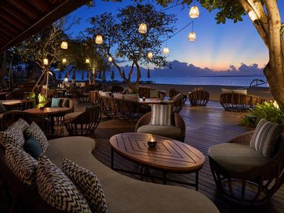 Terrasse d'hôtel confortable avec sièges et lanternes au crépuscule avec vue sur la mer.
