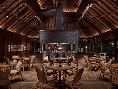 Salon confortable avec mobilier en bois et cheminée dans un bâtiment rustique ouvert.