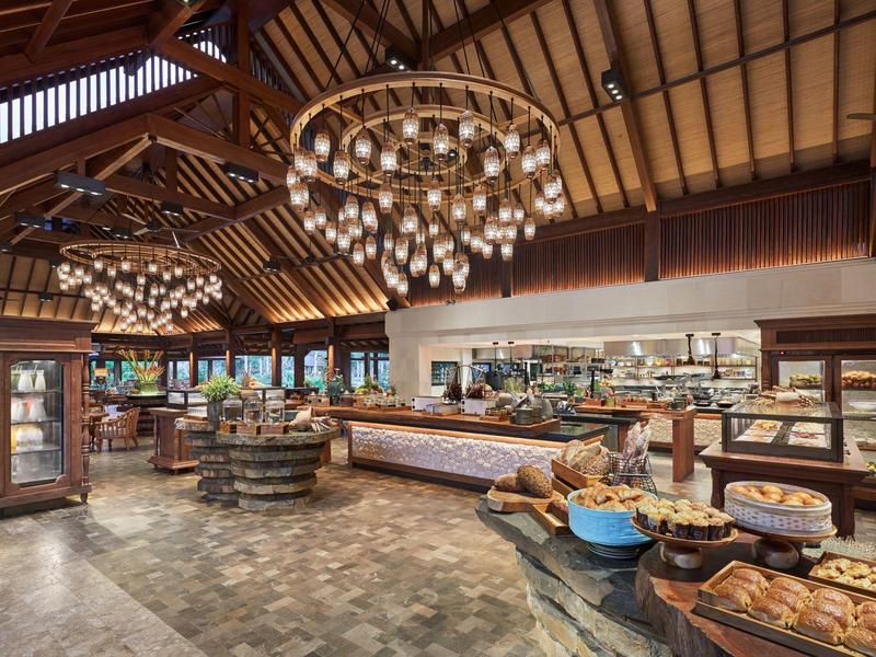 Une salle à manger d'hôtel rustique et chaleureuse avec plafond à poutres en bois et lustres modernes.