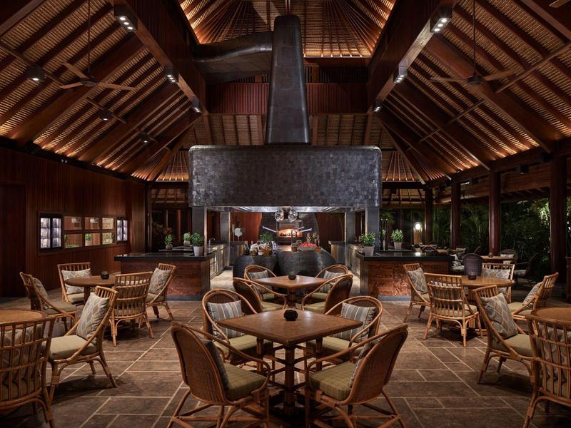 Salon confortable avec mobilier en bois et cheminée dans un bâtiment rustique ouvert.