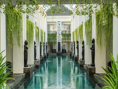 Long indoor pool with statues and hanging plants in a hotel