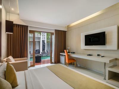 Nowoczesny pokój hotelowy z łóżkiem, biurkiem, telewizorem i dostępem do tarasu.