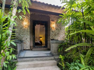 Wejście do pokoju hotelowego z ciepłym oświetleniem i bujną zieloną roślinnością.