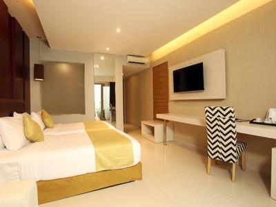 Nowoczesny pokój hotelowy z dwoma łóżkami, telewizorem i biurkiem z krzesłem w ciepłych kolorach.