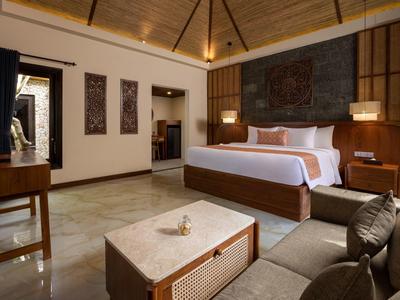 Elegancki pokój hotelowy z dużym łóżkiem, sofą, drewnianymi meblami i ciepłym oświetleniem.