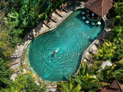 Überblick über einen tropischen Pool mit einer Person, umgeben von üppiger Vegetation und Hängematten.