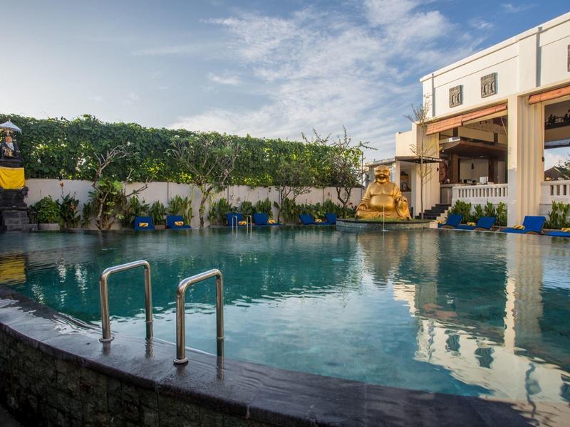 Zapraszający zewnętrzny basen hotelowy z zielenią i niebieskim niebem.