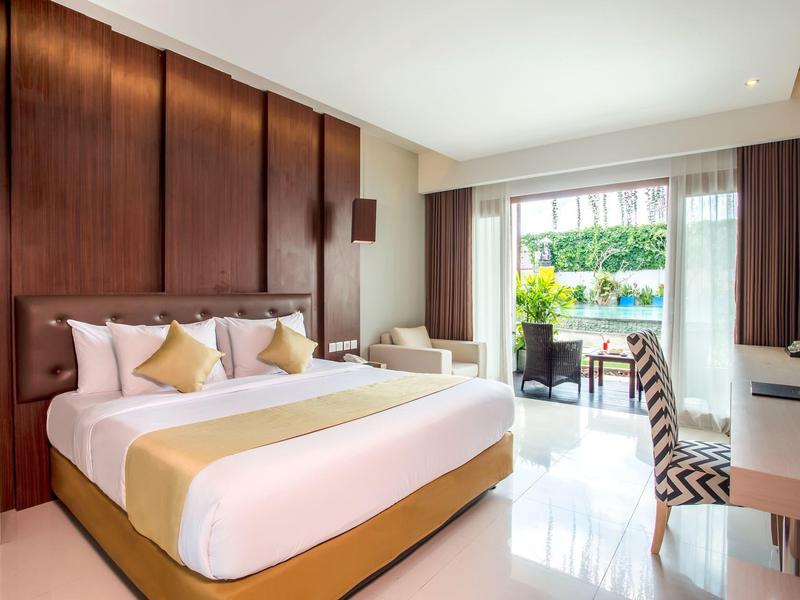 Jasny pokój hotelowy z dużym łóżkiem podwójnym, biurkiem i tarasem z widokiem na basen.