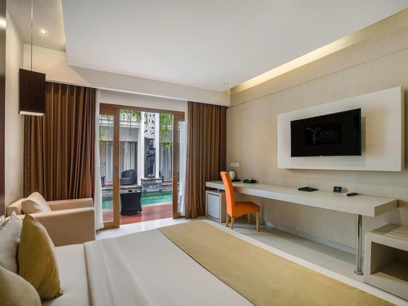 Nowoczesny pokój hotelowy z łóżkiem, biurkiem, telewizorem i dostępem do tarasu.