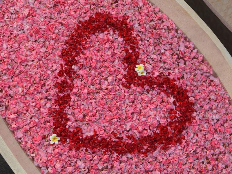 Serce z czerwonych kwiatów na łóżku z różowych płatków, dekoracyjnie ułożone.