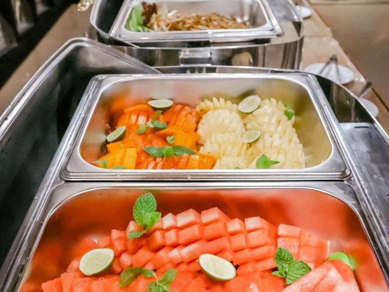 Bufet z kilkoma gorącymi potrawami, w tym misternie ułożoną rybą z plasterkami limonki.