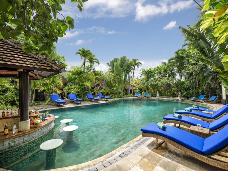 Basen z niebieskimi leżakami i stołkami barowymi w tropikalnym hotelu.