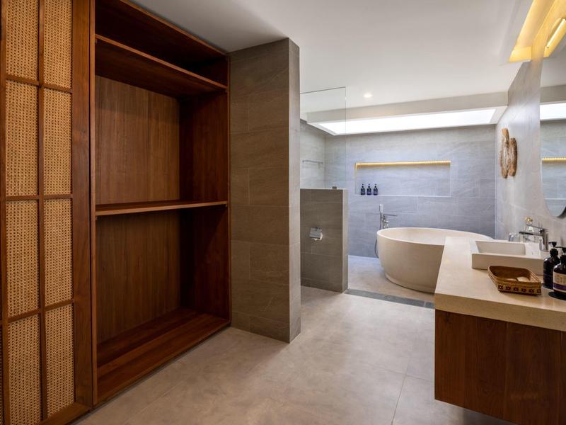 Nowoczesna łazienka z wolnostojącą wanną i otwartą drewnianą szafą.