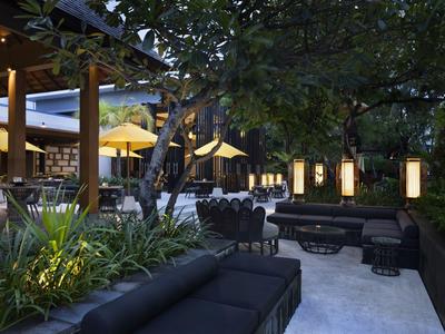 Gemütlicher Außenbereich eines Hotels mit Sitzgelegenheiten und Beleuchtung bei Dämmerung.