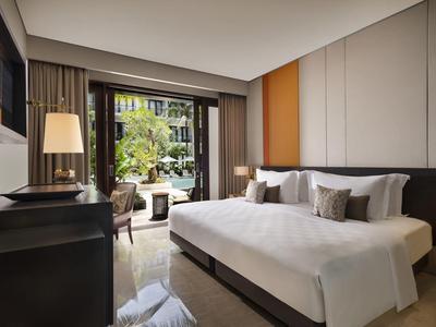 Habitación de hotel moderna con cama grande, balcón y vista a un jardín con piscina.