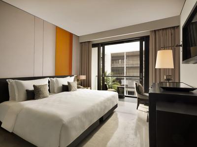 Habitación de hotel moderna con cama grande, escritorio y balcón con vista al exterior.