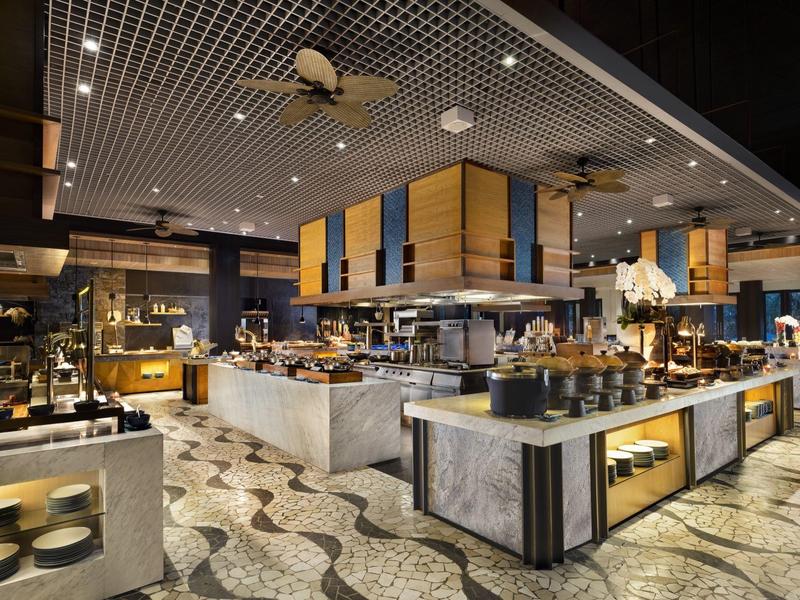 Buffet de hotel moderno con varios platós y decoración elegante en un área espaciosa.