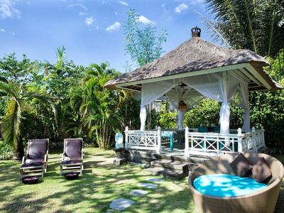 Garten mit tropischem Pavillon, zwei Liegestühlen und einem runden Pool bei sonnigem Himmel.