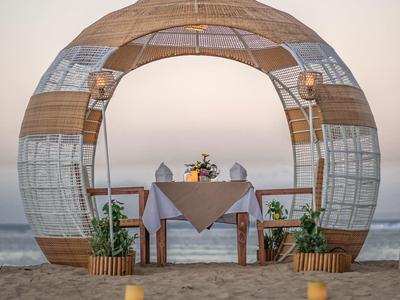 Struttura a cupola in bambù sulla spiaggia con tavolo e candele.