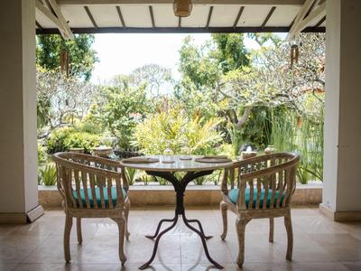 Area coperta con due sedie e un tavolo, vista su un giardino verde.