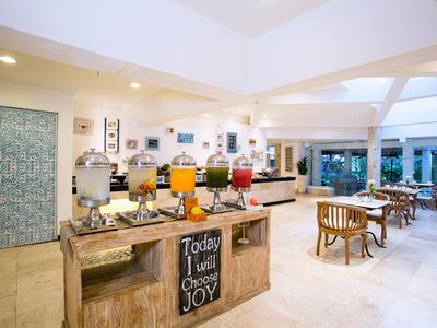 Interno spazioso di un hotel con buffet di succhi colorati e tavoli in legno chiaro.